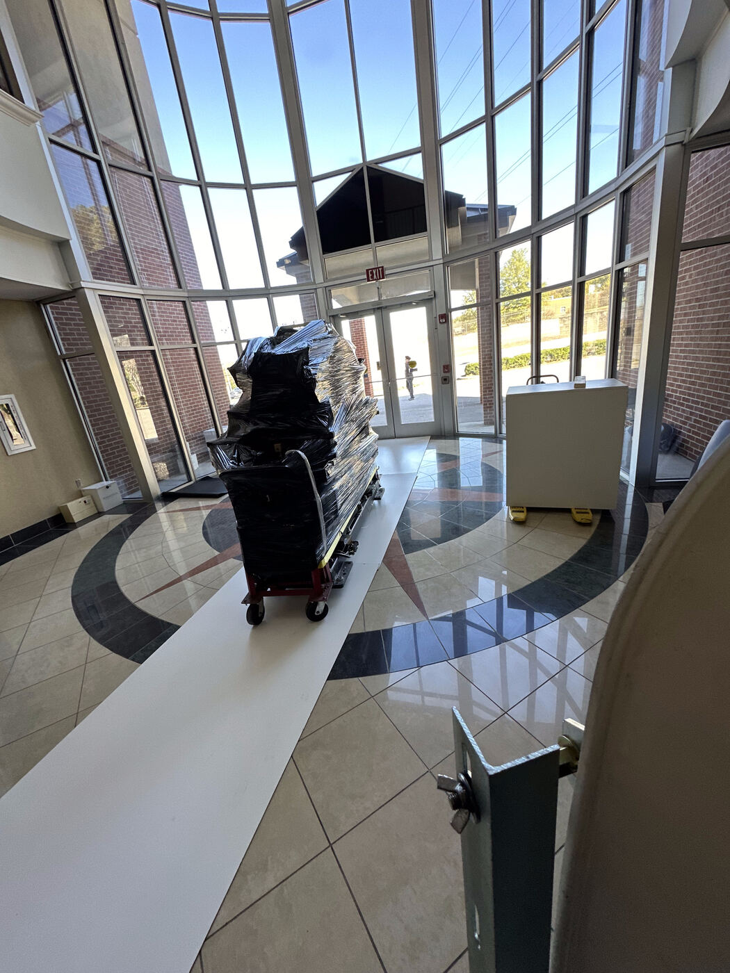 Wrapped CT components rolled through hospital lobby over floor protection