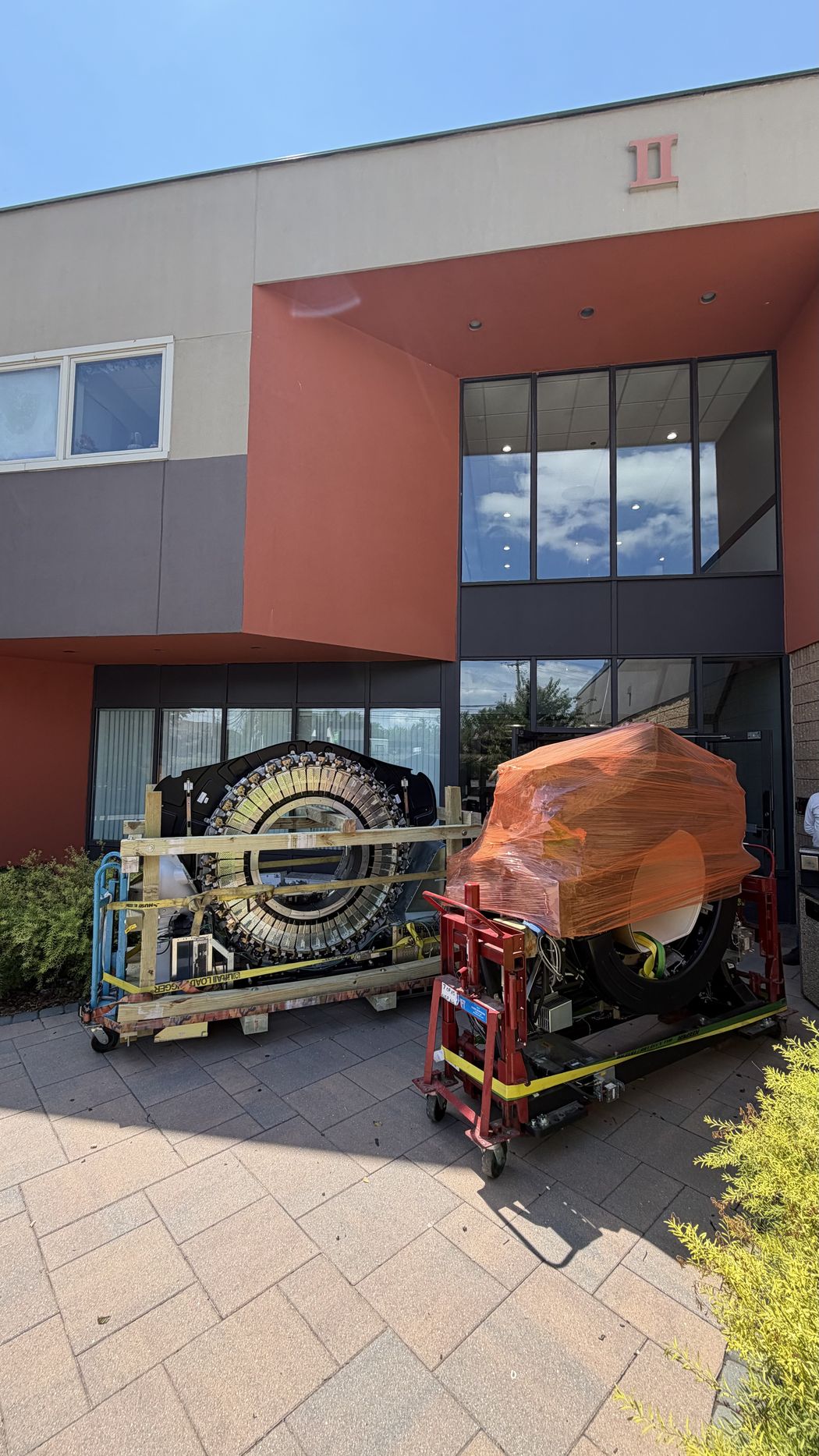Crated detector ring and shrink-wrapped gantry staged at the building entrance
