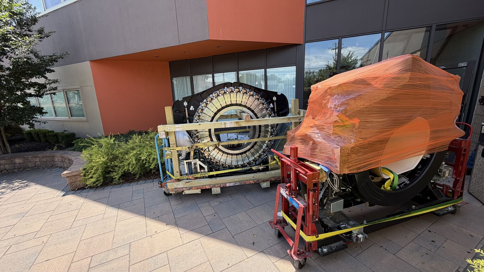 PET detector ring crated on a skid next to the shrink-wrapped PET/CT gantry staged outside the building